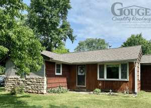 small residential home with green grass and gouge logo in upper right corner