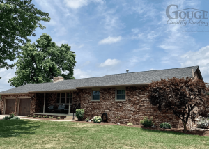 front corner view of residential brick home, clear blue sky in background and gouge logo in upper right corner