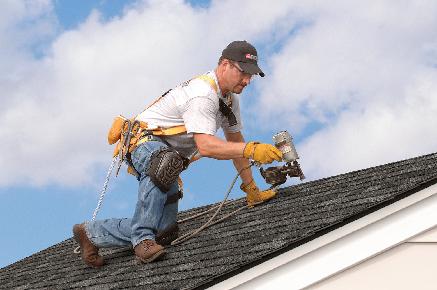 professional worker installing asphalt shingles on residential roof