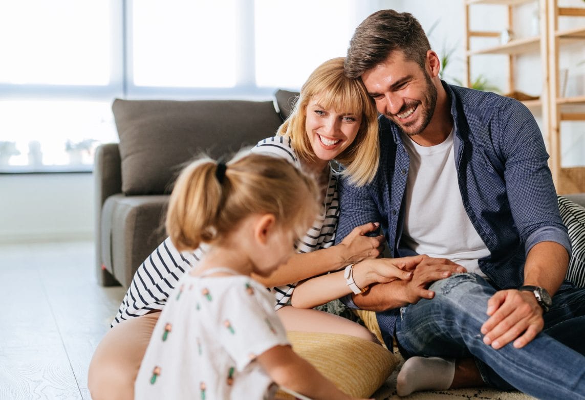 smiling couple with young daughter in front