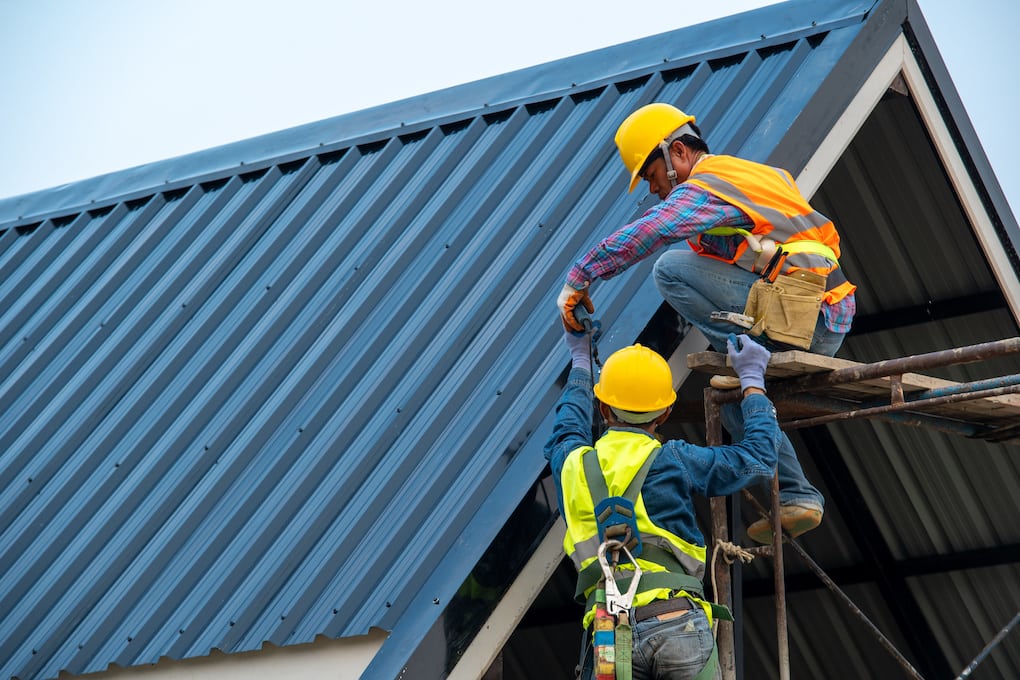 two roofers installing blue metal roofing