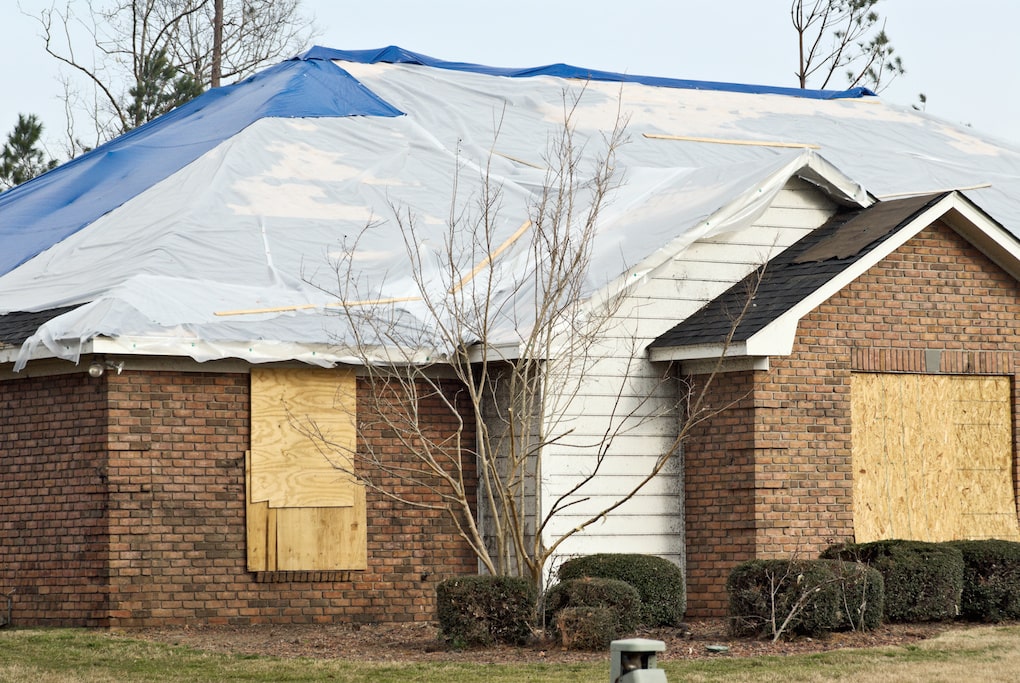 brick home with tarp over roof; how to tarp a roof