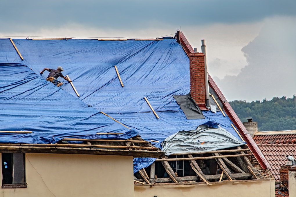 roofer placing tarp on roof; how to tarp a roof