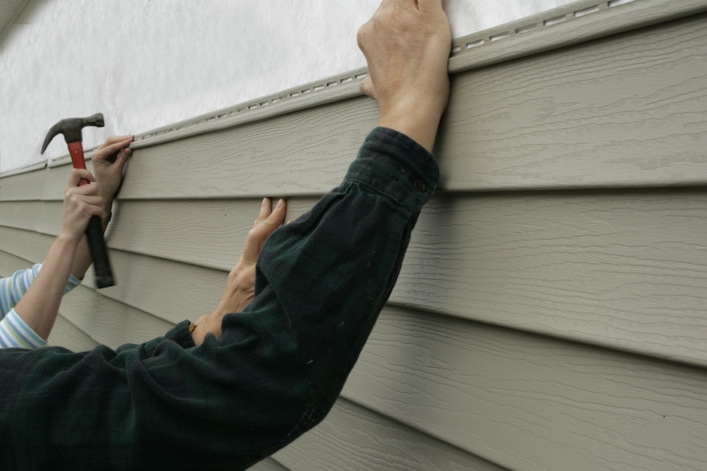 Workers installing siding on a house for roof color combinations 