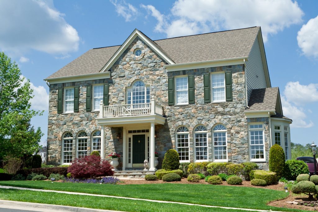 Landscaped stone siding and gray roof color combinations single family house. 