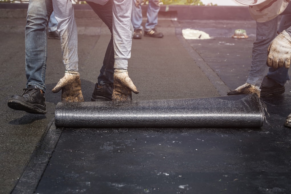 workers rolling flat roof installation materials 