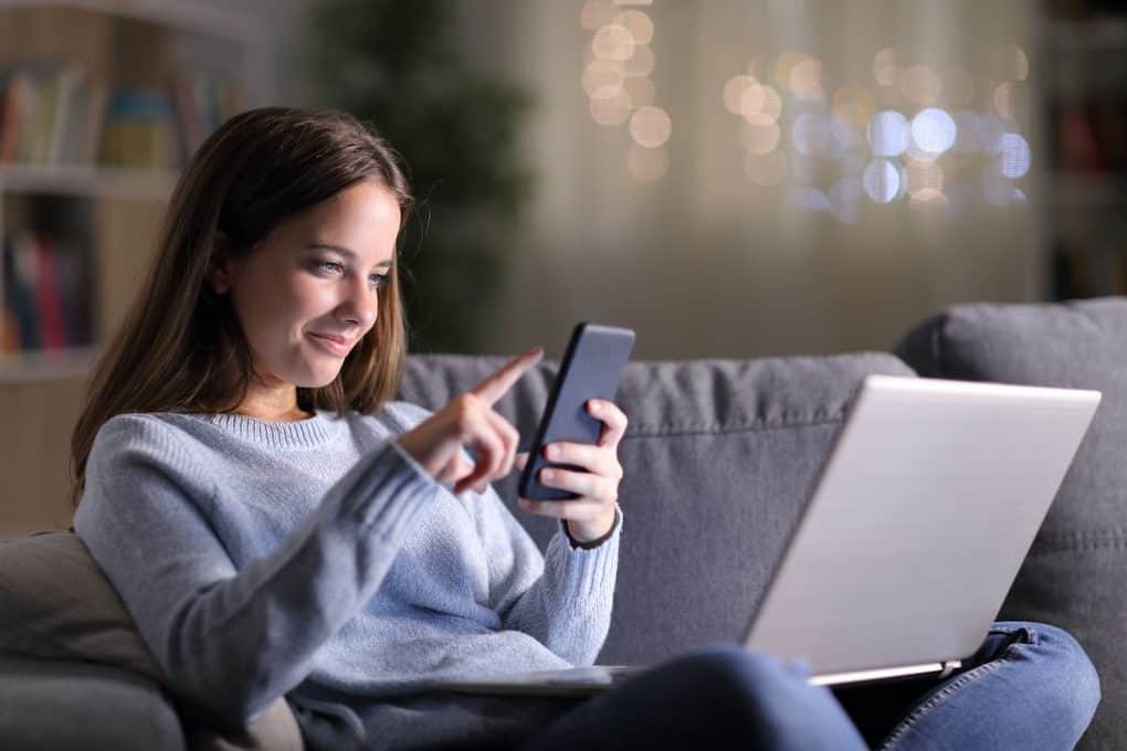 young woman sitting on couch with cell phone in hands; roof installation tips