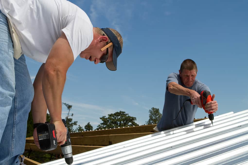 two men installing metal roof with drills; roof installation tips