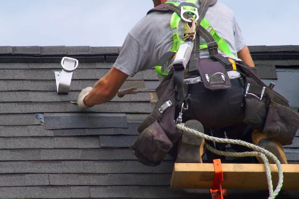 worker on roof showing roof installation tips while wearing a safety harness