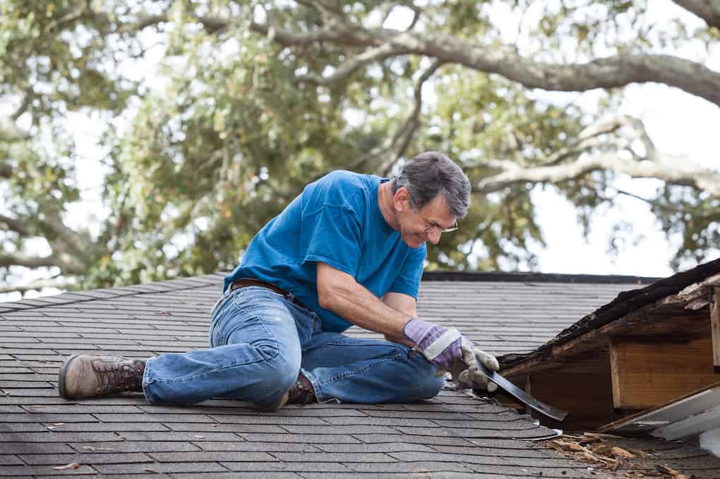 old man on roof showing how to find a roof leak with crowbar
