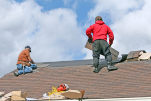 Two woerkers on a roof adding shingles. Planning For A Roof Replacement? Here's Our Expert Guide To Help You Prepare!